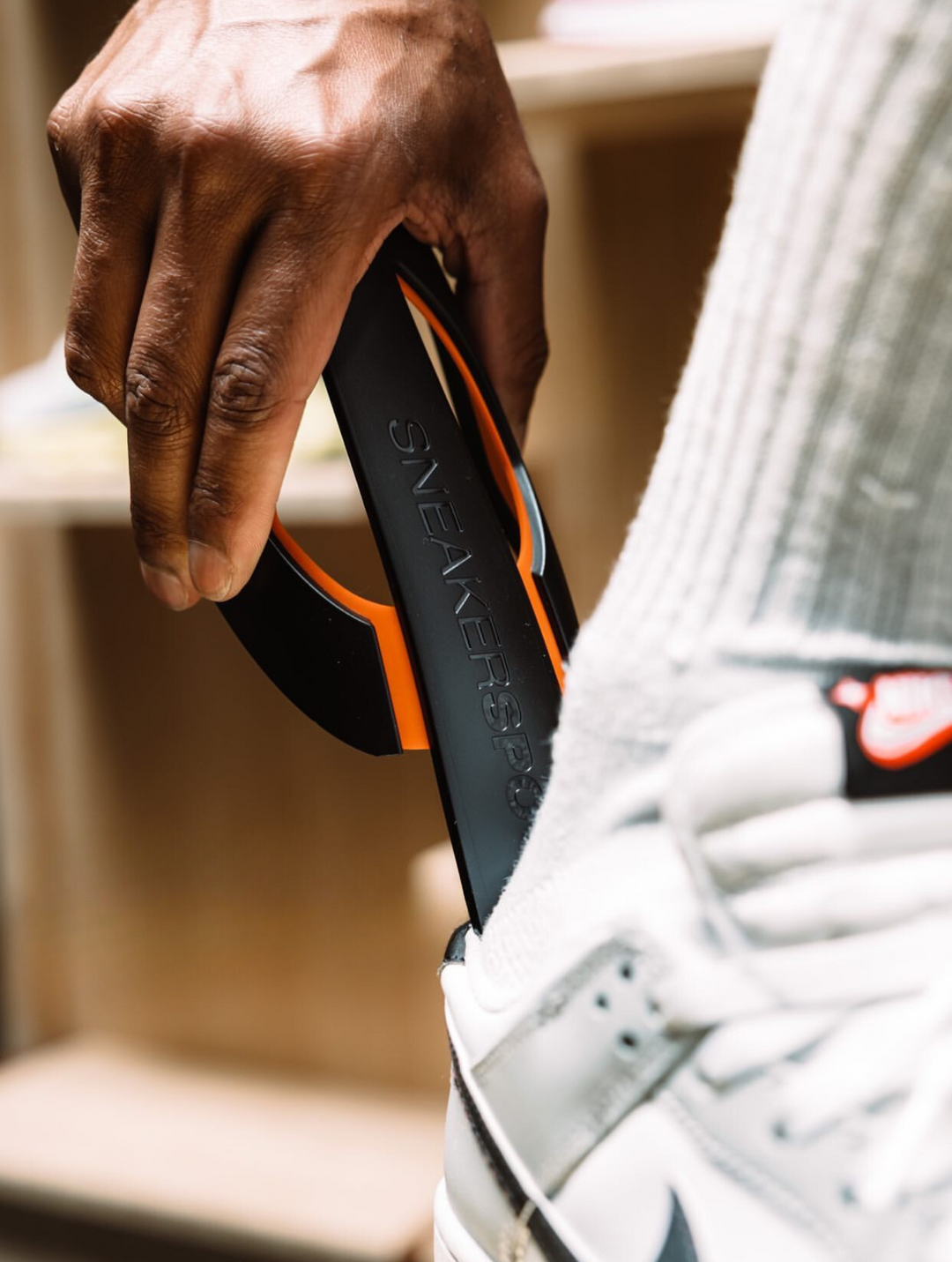 Persoon gebruikt Sneakerspoon als schoenlepel om sneakers gemakkelijk aan te trekken